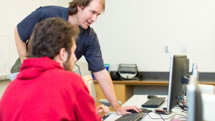 Mark Lewis at computer with student