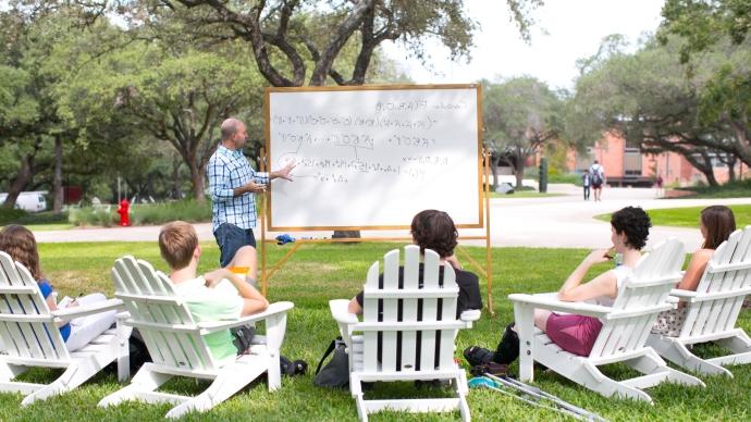 Math professor and students around a whiteboard outside