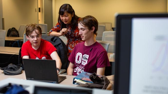 Hoa Nguyen and two students work at a laptop discussing math modeling.