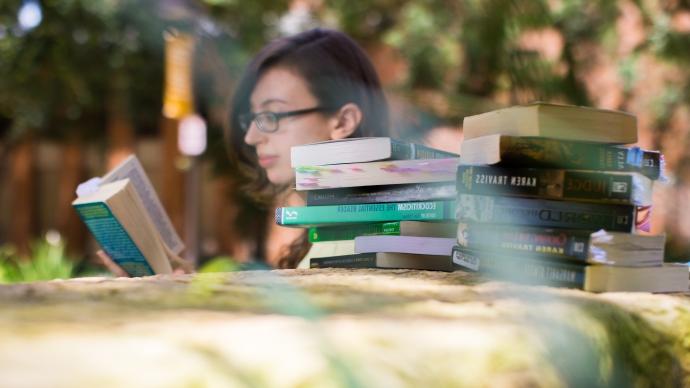 Alex Holler reading outside with a stack of books