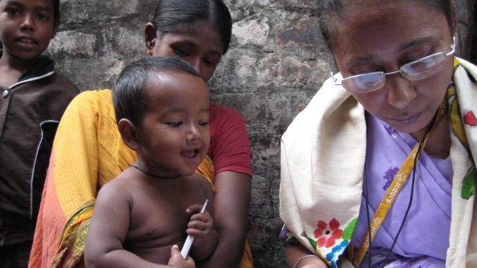 Three children in Bangladesh watch a nurse document administering medication