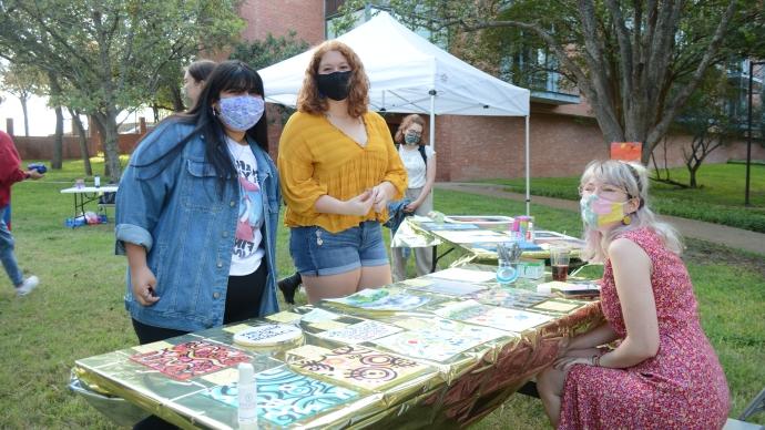 3 students smiling at outdoor table