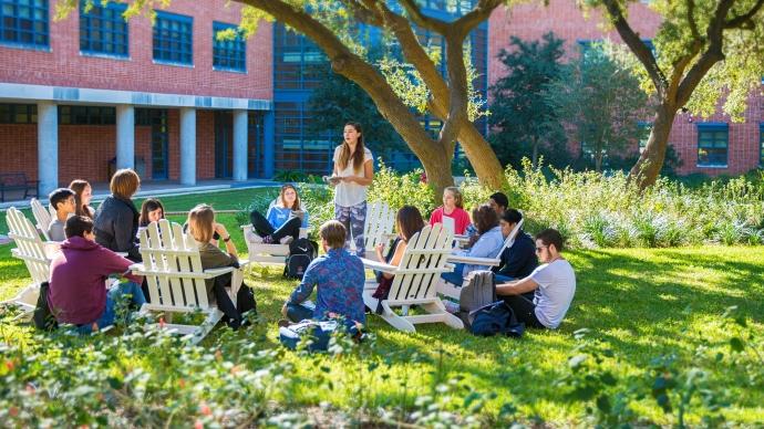 An class sits in the grass and Adirondack chairs next to Northrup Hall