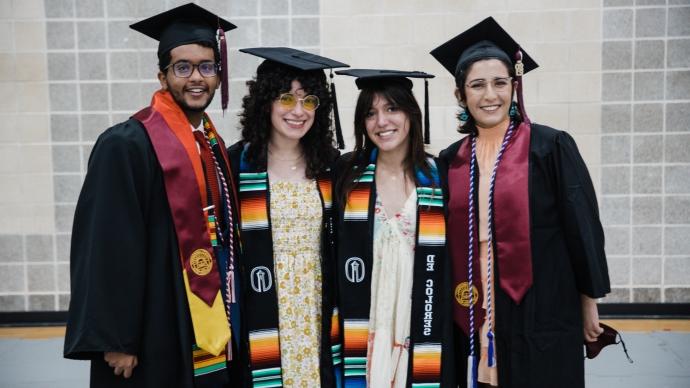 four class of 2021 graduates wear regalia and smile in sams gym