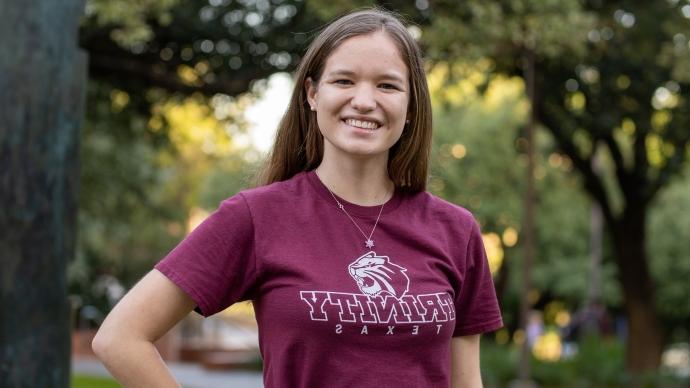 katie davis smiles on trinity's campus wearing a trinity shirt