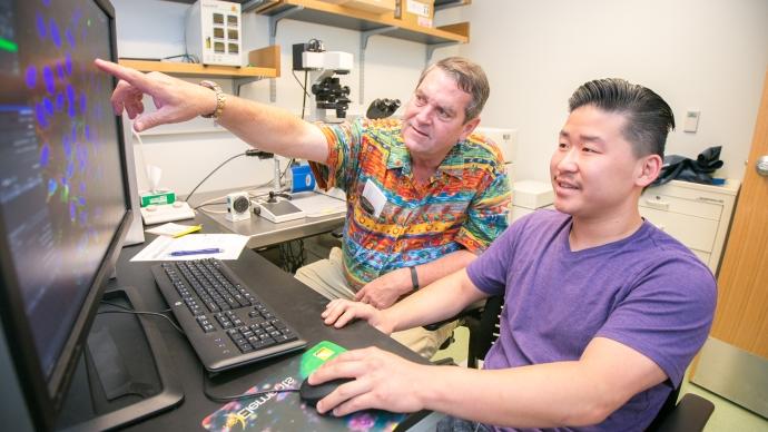 Jimmy Roberts instructs a student at a computer 