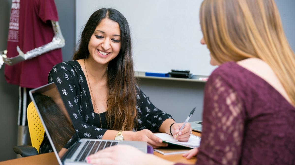 student holding pen smiling in writing center