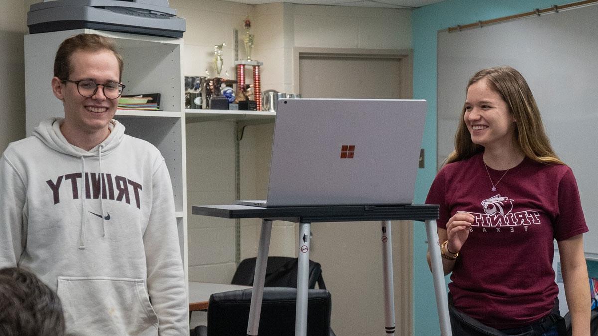 Trinity debate students stand by laptop